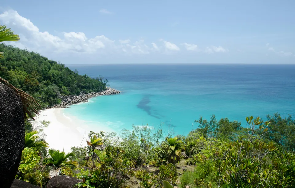 White-sand cove with turquoise water beneath a green hillside
